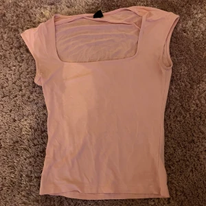 Ljusrosa topp med fyrkantig ringning - Supersöt ljusrosa topp från Gina Tricot med fyrkantig ringning och ärmlös design. Toppens material är mjukt och stretchigt, perfekt för en chill och trendig look. Passar dig som gillar enkla men snygga basplagg.