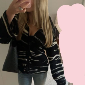 Svart och vit kofta med zebra-mönster - Säljer en svart kofta med vit zebra-mönster. Koftan har långa ärmar  och är i en loose passform. Perfekt för dig som vill sticka ut med ett coolt mönster. Passar till jeans eller kjol för en trendig look. Säljs inte längre!