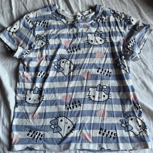 HelloKitty t-shirt - En super gullig Hellokitty magtröja som har kortare armar och suuper gulligt mönster med hjärtan på, den är från barnavdelningen på H&M men texten är borta som man ser på sista bilden så vet inte mått eller sånt. säljer dem för att jag inte använder den längre. Skulle gissa att storleken är XS eftersom den är från barnavdelningen. Priset kan diskuteras!!
