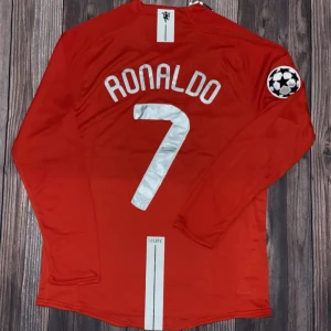 Manchester United Ronaldo 7 Finaltröja 2008 - Champions League-finaltröja från Manchester United 2008 med Ronaldo 7 på ryggen. Röd långärmad modell med broderat klubbmärke, gult finaltryck och AIG-logga på bröstet. Materialet är lätt och andas, perfekt för match eller samling. Champions League-märke på ärmen. FINNS I STORLEK S, M, L, XL och XLL.