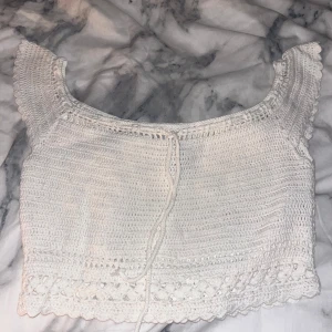 Vit virkad croppad topp från H&M Divided - Superfin vit croppad topp från H&M Divided i virkad bomull. Toppen har korta ärmar med söt volangkant och ett knytband fram. Perfekt till sommaren och ger en chill boho vibe. Passar dig som gillar detaljer och vill ha något unikt i garderoben.