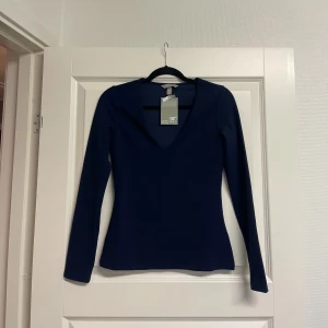 Marinblå långärmad polotopp - Snygg marinblå långärmad polotopp från Hm  Toppens material är mjukt och stretchigt, vilket gör den bekväm och följsam. Passformen är slim och den har en stilren, enkel design utan mönster eller extra detaljer.