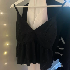 Svart linne med volang - Supersöt svart linnetopp med små prickar och volang nedtill. Storlek S🤍