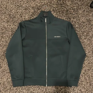 Grön tröja med dragkedja - Les Deux - En fin grön tröja med dragkedja från Les Deux med stilren design och hög krage stil. Har använts väldigt sparsamt och noggrant. Inga direkt tecken på att den har använts eller något liknande. Säljer denna pga den har blivit för stor för mig. Önskas fler bilder så är det bara att hojta till. Kvitto finns!