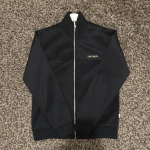 Svart tröja med dragkedja - Les Deux - Säljer denna fina svarta tröja med dragkedja från Les Deux. Har använts, dock inga direkt tecken på att den har använts eller något liknanden. Säljer denna då den har blivit för stor för mig. Önskas fler bilder så är det bara att hojta till. Kvitto finns! Ny pris cirka 1000kr.