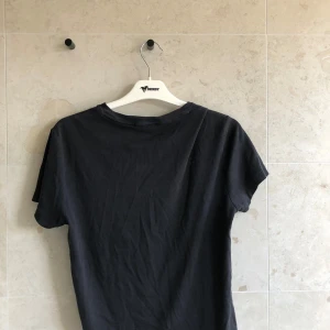 Svart t-shirt Polo Ralph Lauren - Svart t-shirt från Polo Ralph Lauren med klassisk rund hals och broderad logga på bröstet. Modellen är custom slim fit och har korta ärmar. Materialet är mjuk bomull som känns skönt mot huden. Perfekt för dig som gillar stilrena och tidlösa plagg.