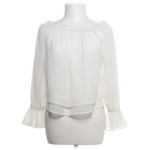 Vit blus - Säljer en söt vit blus med diskret prickigt mönster och volangdetaljer vid ärmslut. Blusen har långärmade transparenta ärmar och en luftig, flowy passform som ger en chill vibe. Perfekt för dig som gillar romantisk och feminin stil.