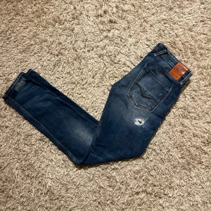 Replay Anbass blå jeans herr med slitningar  - Snygga Replay Anbass jeans i mörkblå tvätt med slitningar. Nytt skick, inga anmärkningar och knappt använda. Klassisk femficksmodell med Replay-logga på läderpatch bak. Slim passform och slitstarkt jeanstyg för skön känsla. Postas antigen samma dag som köp eller dagen därpå, kostar 500kr ifall man kan mötas🙌💯