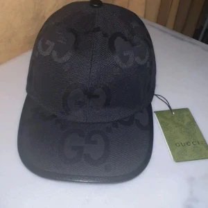 Gucci keps  - Snygg svart keps från Gucci med GG-logga i ton-i-ton över hela kepsen. Kepsen är i mycket bra skick och helt stilren. Made In italy, tveka it på prisförslag