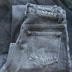 Svarta wide jeans från NA-KD, strl 34 - Säljer ett par svarta/mörkgråa jeans från NA-KD i storlek 34. Modellen har en wide passform med raka, breda ben och hög midja. Nypris 599kr, endast använd fåtal gånger.