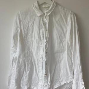 Vit linneskjorta från H&M, strl 36 - Vit skjorta från H&M i 100% linne, storlek 36. Klassisk krage, knappar framtill och långa ärmar. Perfekt för en chill och clean look, lätt att matcha med jeans eller shorts. 