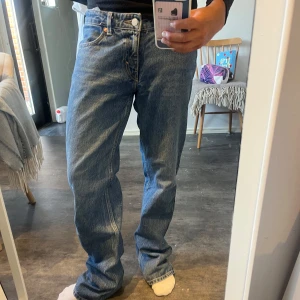 Weekday Arrow blå straight jeans 27/32 - Säljer ett par blå Arrow jeans från Weekday i modellen low straight. Klassisk femficksdesign, låg midja och raka ben. Jeansen är i bomull och har en snygg tvättad blå färg som passar till allt. Perfekta för dig som gillar en avslappnad och tidlös look.
