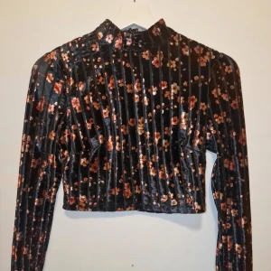 Svart blommig crop topp - Svart sammetströja med blommigt mönster. Snygg både till utekvällen och till vardags.