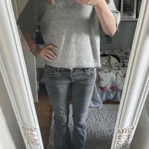 Grå bootcut jeans med låg midja - Säljer ett par grå jeans med snygg bootcut och låg midja. Jeansen har klassisk femficksdesign och är tillverkade i mjukt denimtyg. Passformen är normal och färgen är en cool, lite tvättad grå ton som passar till allt. Perfekt för dig som gillar avslappnad stil. 