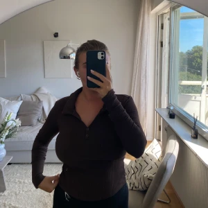 Brun ribbad pikétröja från vero Moda  - Tröjan har knappar framtill och är i en tight passform. Materialet är mjukt och stretchigt.