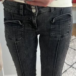 Svarta Nelly jeans - Snygga svarta bootcut jeans från Nelly med coola fickdetaljer framtill och klassiska bakfickor. Jeansen har låg midja och är gjorda i stretchigt denim för skön passform. Dubbelknäppning framtill och markerade sömmar ger en trendig vibe. De har slitningar längst ner på baksidan men ingenting man tänker på. Tveka inte att skriva vid frågor!💕💕