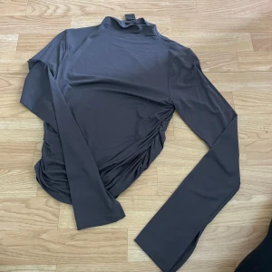 Långärmad topp - Långärmad topp från GINA TRICOT, med liten polo och scrunchat i sidorna. Nypris 299kr. Köparen står för frakten. Pris kan diskuteras vid snabb affär.