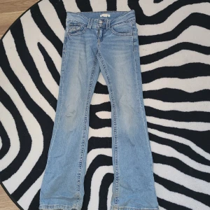 Bootcut jeans ljusblå Gina Tricot 152 - Ljusblå jeans från Gina Tricot i storlek 152. Klassisk femficksmodell med bootcut-ben och låg midja. Jeansen har snygga slitningar och kontrastsömmar, tillverkade i mjukt bomullsmaterial. Perfekt för dig som gillar retrovibe och avslappnad stil.