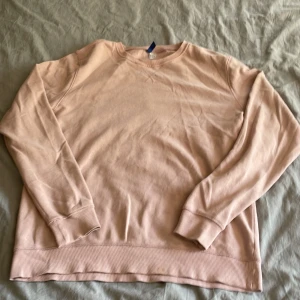 Ljusrosa sweatshirt från H&M Divided - En enkel och chill ljusrosa sweatshirt från H&M Divided i storlek L. Tröjan har rund hals, ribbade muddar och är gjord i mjuk bomull. Perfekt för att slänga på sig när man vill vara bekväm. Passar dig som gillar basic och stilrent. Storlek L