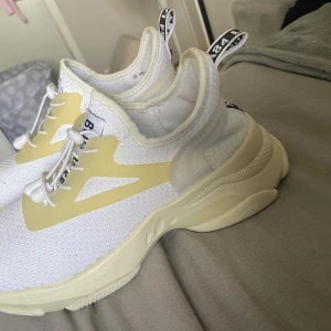Vita sneakers från dinsko  - Säljer ett par fräscha vita  sneakers med mesh-ovandel och ljusgula detaljer på sidorna. Skorna har snörning med snabblås och en chunky platt sula i syntet. Perfekt för dig som gillar stilrena och sportiga vibes.