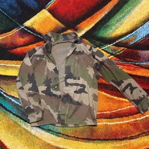 Camouflage overshirt med knappar SÄLLSYNT💫✨ Vintage perfekt skick  - Säljer en grön, brun och beige camouflage overshirt med ståkrage och långa ärmar. Jackan har två vertikala dragkedjefickor på bröstet och knäppning framtill. Perfekt för dig som gillar militärstil och vill sticka ut med coola detaljer. Storlek S skick 10/10 DM för fler bilder och frågor 🌈🌪️⚡️✨