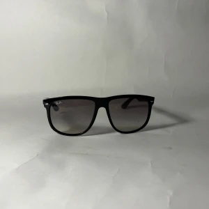 Rayban boyfreind  - Snygga svarta Ray-Ban solglasögon i klassisk Wayfarer-modell. Bågarna är i blank plast och har mörka tonade glas. Diskret Ray-Ban-logga på skalmen och framtill. Perfekta för en cool och tidlös stil.