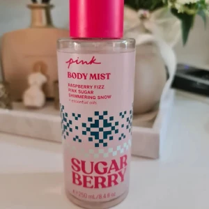 Pink Sugar Berry Body Mist 250ml - Fräsch body mist från Pink i doften Sugar Berry med toner av hallon, sockrig sötma och shimmer. Flaskan är genomskinlig med rosa detaljer och ett rosa lock. Innehåller eteriska oljor och är vegansk. Rymmer 250 ml och har en modern, ungdomlig design. Provsprutad en gång