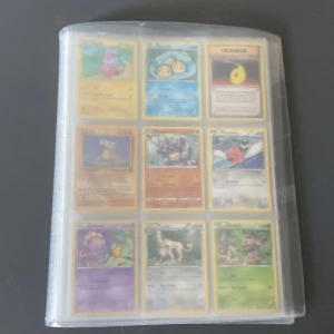 Pokémonkort Samlarpärm - En samlarpärm fylld med Pokémonkort, inklusive flera holografiska och GX/V-kort. Perfekt för dig som älskar Pokémon och vill utöka din samling med både klassiska och moderna kort. Pärmen innehåller blandade Pokémon och tränarkort – en riktig skatt för fans! (Den är helt full).