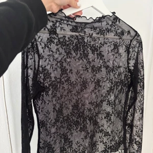 Spetstopp - Säljer en långärmad spetstopp med blommigt spetsmönster. Toppen har en lätt vågig kant vid halsen. Perfekt för att styla med en svart kjol med ett par höga boots till. Har tyvärr bara användt toppen 1 gång. Toppen är en L men anser att den sitter bra på mig som har M. Den är lite liten i storlek. Toppen är från NAKD! 