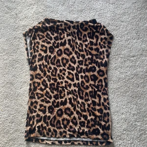 Leopardmönstrad topp XS Black Label - Säljer en snygg leopardmönstrad topp från The Black Label Collection i storlek XS. Toppen har en tight passform och är ärmlös, perfekt för dig som vill sticka ut. Färgerna går i brunt, svart och beige och materialet känns mjukt och stretchigt.