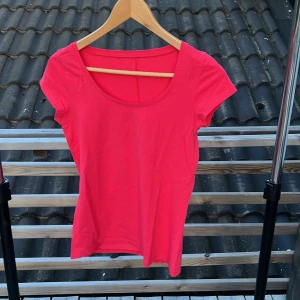 Rosa topp från Gina Tricot - En enkel och snygg rosa topp från Gina Tricot med rund halsringning och korta ärmar. Modellen är figurnära och tillverkad i mjuk bomull med lite stretch för extra komfort. Perfekt att matcha med jeans eller kjol för en fräsch look.