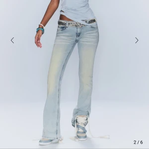 Ljusblå bootcut jeans med slitningar - Säljer ett par ljusblå bootcut jeans med snygga slitningar och tvättade detaljer. Jeansen har klassisk femficksdesign och låg midja. Perfekta för dig som gillar en avslappnad och trendig look.