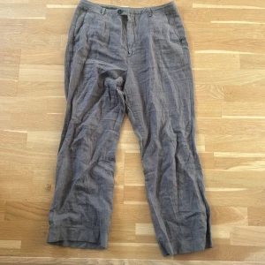 Grå linnebyxor med croppade ben - Snygga grå linnebyxor med raka ben och klassisk passform från Massimo dutti.  Byxorna har hällor för bälte, sidfickor och stängs med dragkedja och knapp. Perfekta för en chill och avslappnad stil under varmare dagar.