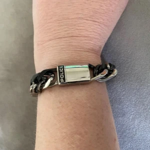 Armband!  - Oanvänt! Snyggt kedjearmband från Police i svart och silverfärgad metall. Breda länkar. Kraftig kedjemodell. Stilrent lås där Police-loggan syns tydligt. Aldrig använt! Tungt och rejält armband! 21 cm långt inklusive knäppe   62 gram vikt   Magnetknäppe.