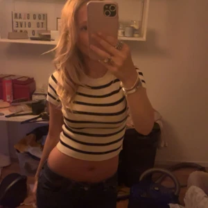 Randig croppad topp - Säljer en croppad topp med svarta och vita horisontella ränder. T-shirten har korta ärmar och rund halsringning. Perfekt för dig som gillar en enkel men snygg stil. Materialet är mjukt och stretchigt typ som en tunn stickad tyvärr aldrig använd för jag tycker den e för kort