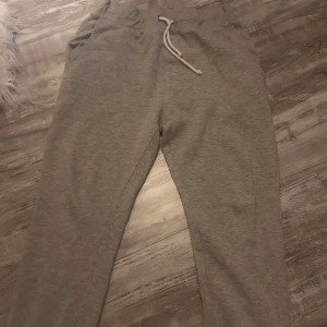 Grå mjukisbyxor med snörning, stl M - Grå mjukisbyxor från C i storlek M. Byxorna har dragsko i midjan, mjukt fleeceliknande foder och bakficka. Perfekta för chill dagar eller när du vill vara extra bekväm.