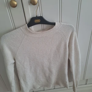 Beige stickad tröja med rund hals - Mysig beige stickad tröja med rund halsringning och ribbade muddar. Tröjan har en klassisk, enkel design och är långärmad. Perfekt att styla med både jeans och kostymbyxor för en clean look. Ganska nopprig men går att fixa lätt med en noppkam nypris 300 mitt pris 70