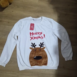 Vit jultröja med renmotiv från PatPat - Vit långärmad tröja från PatPat med rött tryck 'Merry Xmas!' och en mjuk applikation av en brun ren framtill. Rund halsringning och ribbade muddar. Perfekt för att maxa julkänslan med ett gulligt motiv.