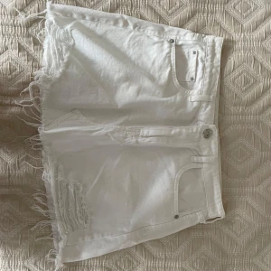 Jeans kjol river island  - Snygga vita jeansshorts med fransig rå kant och slitningar framtill. Klassisk femficksmodell med knapp och dragkedja. Perfekta för sommaren och ger en avslappnad vibe till din outfit.