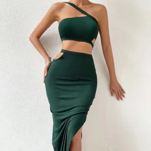 Mörkgrön tvådelad set - Snygg mörkgrön top med en  långkjol i tight passform med hög midja och coola cut-out detaljer vid midjan. Kjolen har en djup slits på sidan som ger en trendig look. Perfekt för dig som vill sticka ut och gillar stilrena plagg med edge.