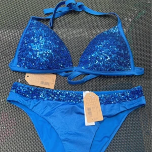 Blå glittrig bikini från Calzedonia - Blått glittrigt bikinisett från Calzedonia i modellen cobey. Triangelbikini med knytband. Nypris 60€, prislappar kvar och aldrig använd💝 