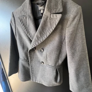 Kavaj - Grå kavaj som är figursydd med knappe framtill