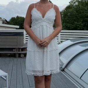 Sommarklänning  - Supersöt vit klänning från Vero Moda med tunna justerbara axelband, v-ringning och volangdetaljer, den har en väldigt diskret/osynlig dragkedja på sidan så att det blir enklare att ta av/sätta på sig klänningen. Klänningen passar perfekt för varma sommardagar eller när man vill känna sig lite extra fin. 