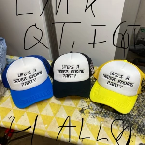 Truckerkepsar med text i olika färger - Tre truckerkepsar med vit front och texten 'Life's a never ending party' broderad. Finns med blå, svart eller gul skärm och mesh. Perfekt statement-accessoar för dig som vill sticka ut. Hatar ai. 