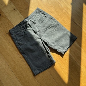 Grå jeansshorts från 157 - Gråa jeansshorts från 157 med klassisk femficksdesign och bälteshällor. Modellen är rak och lite längre, perfekt för en chill och avslappnad stil. Materialet är denim och färgen är en snygg tvättad grå som passar till allt.