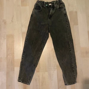 Svarta loose jeans med resårmidja - Säljer ett par svarta jeans med cool tvätt och resår i midjan. Byxorna har en loose passform, raka ben och klassiska fickor både fram och bak. Perfekta för dig som gillar avslappnad stil och vill ha något bekvämt men ändå snyggt.