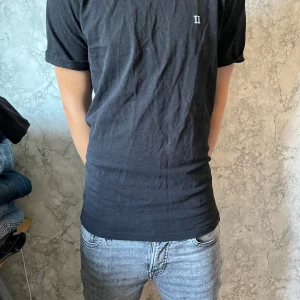 Svart t-shirt från Les Deux - Svart t-shirt från Les Deux i storlek M. Klassisk modell med korta ärmar och rund halsringning. Liten vit broderad logga på bröstet. Skön bomullskvalitet som passar perfekt till jeans eller shorts. Pris ej hugget i sten vid snabb affär. hör av dig vid minsta fundering!