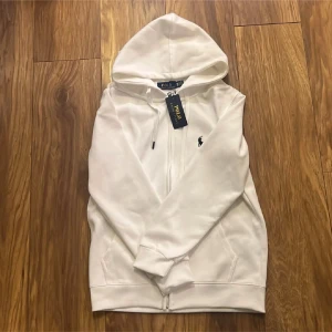 Vit Ralph Laurent zip up  - Säljer denna nya Ralph Laurent tröjan för billigt pris då den inte kommit till användning men har skräpat ett tag hemma nu! 