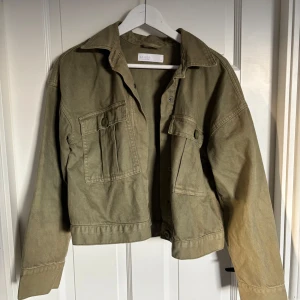 Olivgrön jeans jacka från Samsa Collection - Snygg olivgrön jeans jacka från Samsa Collection med klassisk krage, stora bröstfickor med knappar och raka ärmar. Jag köpte den på Ullared Gekås, däremot kommer jag inte ihåg hur mycket den kostade, sedan finns den inte online heller. Alltså sätter jag ett pris på 99kr. Den är aldrig använd men har ingen prislapp kvar.
