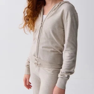 Beige cardigan jacka med huva - Mysig beige cardigan jacka med huva och dragkedja framtill. Jackan har ribbade muddar, snörning i midjan och är långärmad. Perfekt för en chill och avslappnad stil.